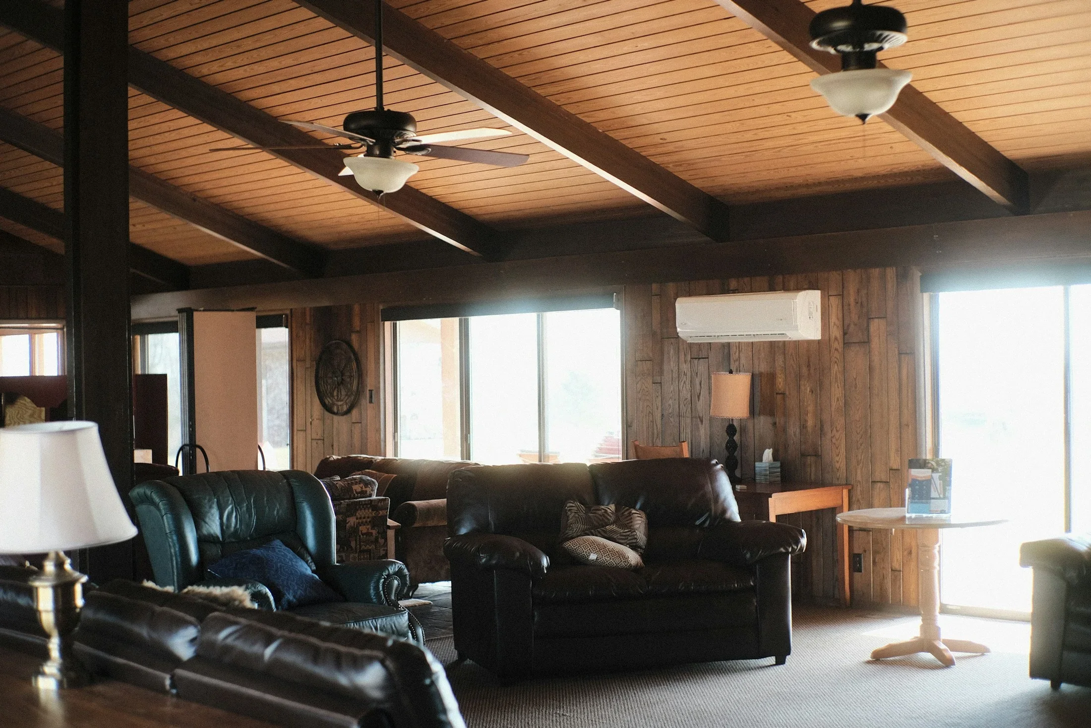 A warm wood-paneled living area with comfortable seating and broad windows
