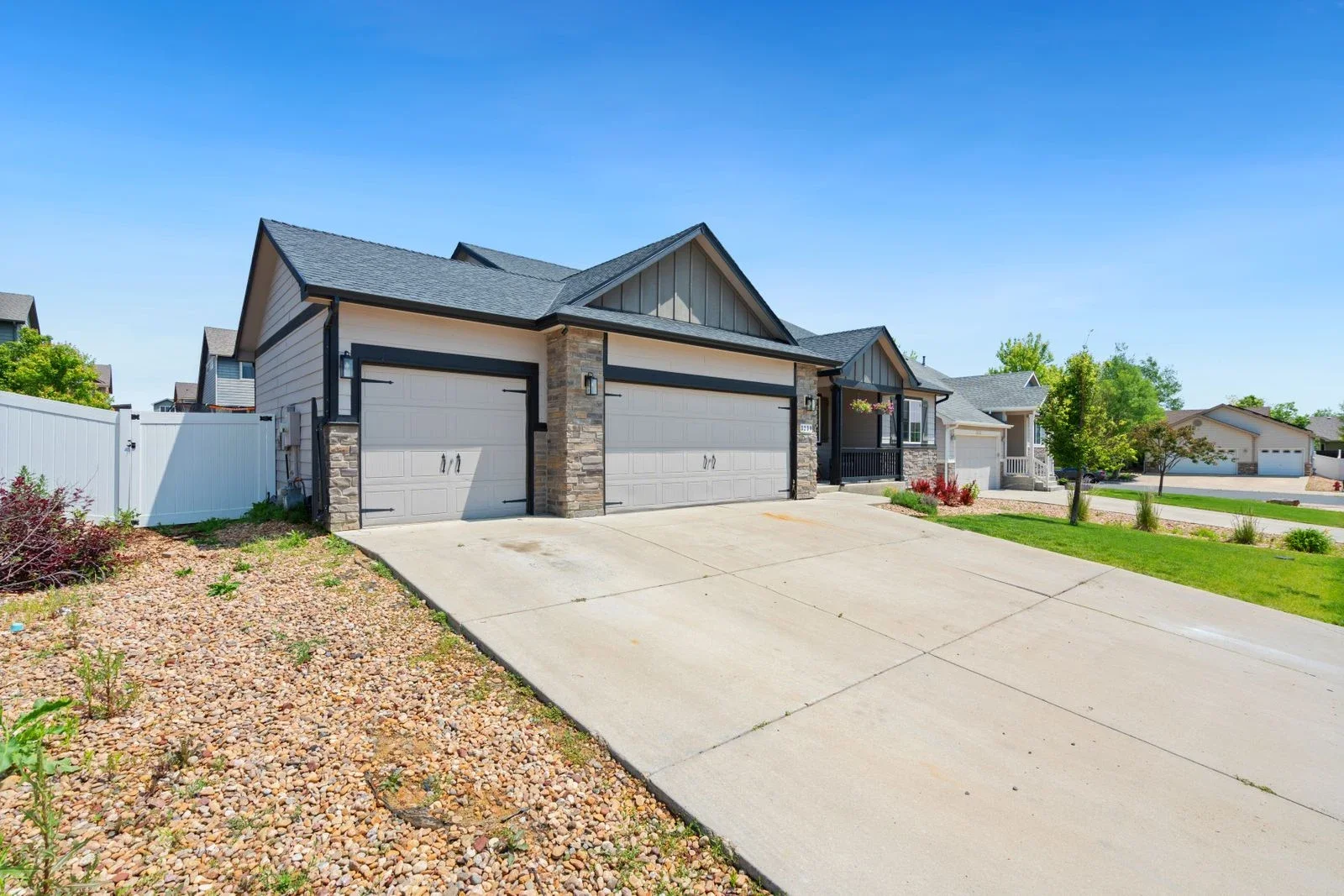 A contemporary suburban home with stone accents, a covered entry, and landscaped front yard